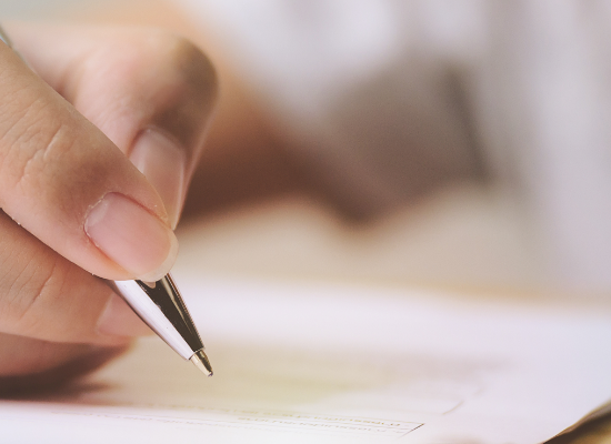 Hand holding pen over form